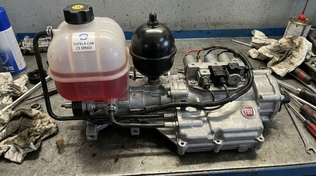 Vue d'un robot hydraulique Dualogic (actionneur de boîte) démonté d'une Fiat 500, montrant le réservoir d'huile et la sphère accumulatrice