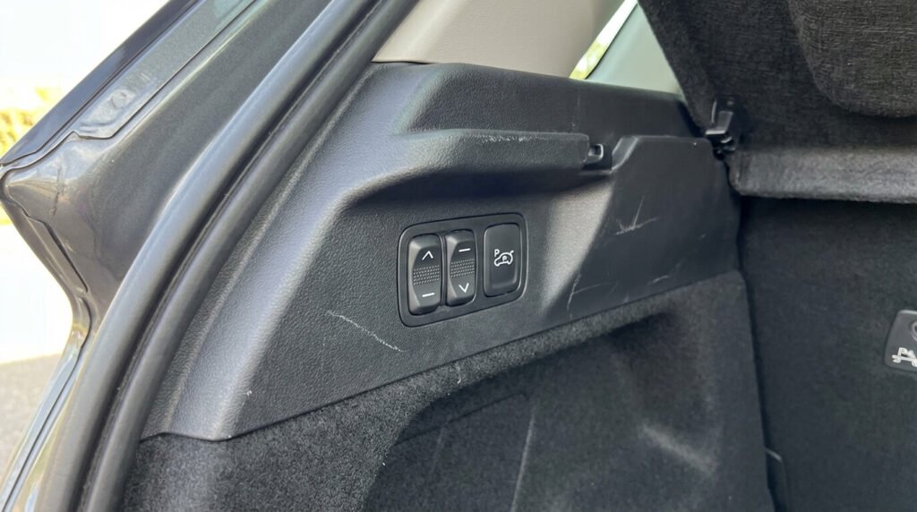 Gros plan sur les boutons de commande manuelle de hauteur situés dans le coffre du C4 Picasso, utilisés pour forcer le réveil du compresseur ou désactiver le système