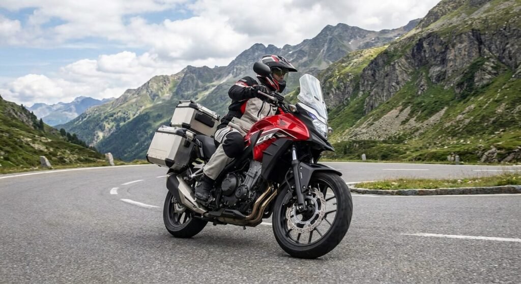 Moto Honda CB 500 X rouge équipée de bagagerie roulant sur une route de montagne sinueuse