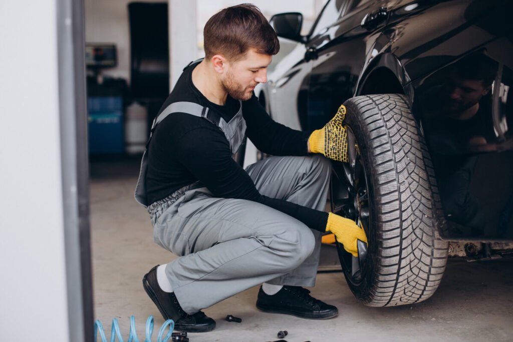 Mécanicien montant un pneu hiver certifié 3PMSF sur une voiture dans un atelier au Luxembourg.