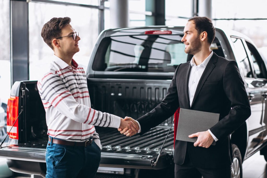 Reprise ou vente à un particulier, quelle solution pour vendre vite ? 3 Vendeur signant un contrat de reprise de sa voiture d'occasion chez un concessionnaire automobile.