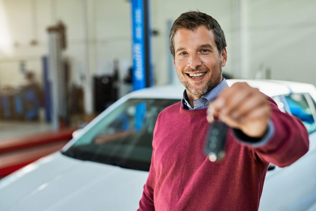Reprise ou vente à un particulier, quelle solution pour vendre vite ? 3 Propriétaire remettant les clés de son véhicule d'occasion à un acheteur particulier après un essai.